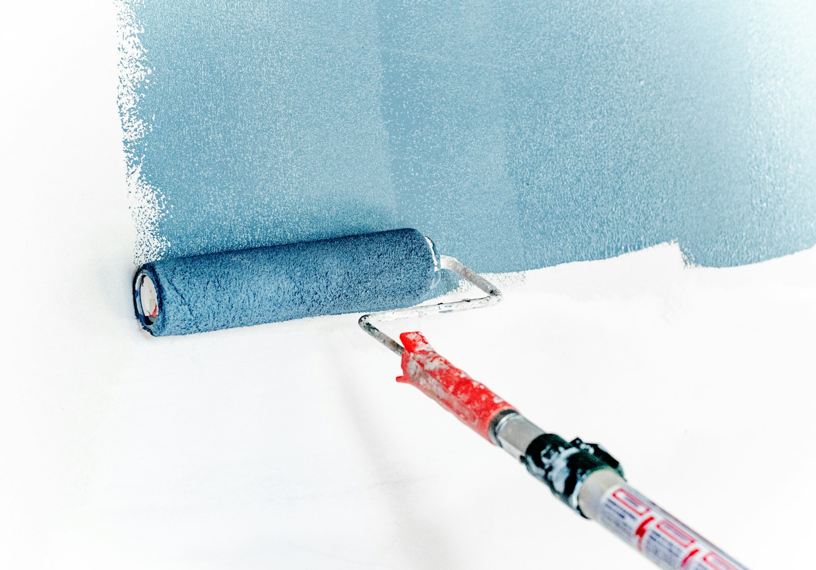 Paint roller applying a clean blue coat to an interior wall